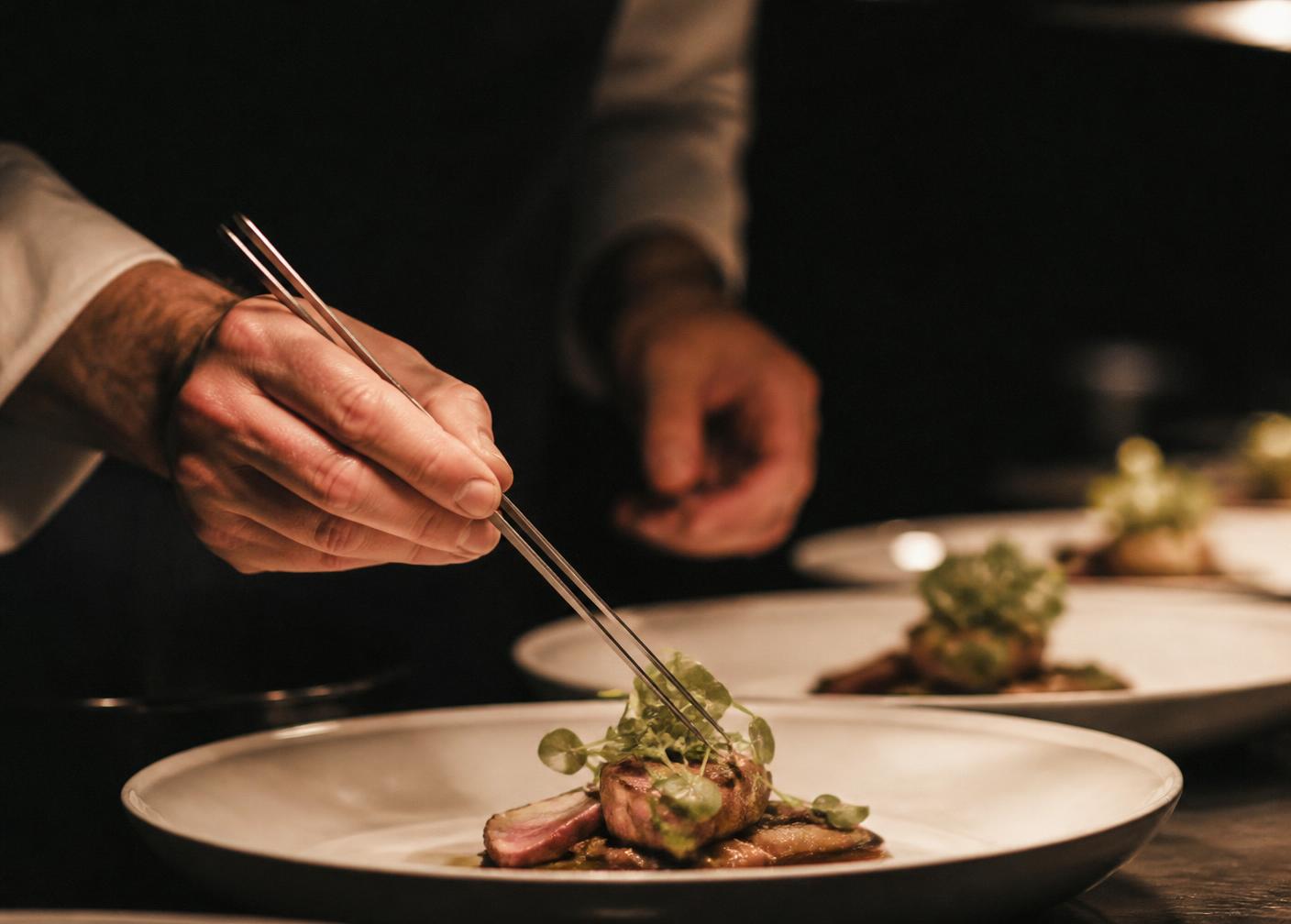Chef plating a dish with tweezers